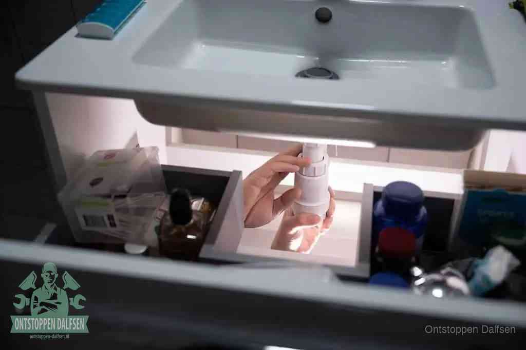 Een pompfles met zeep boven een wastafel, de heet water en afwasmiddel-methode om een vetprop in de afvoer los te maken in Dalfsen
