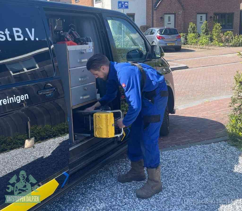 Een monteur pakt buiten op de oprit gereedschap uit de bedrijfsbus, het moment om een professional in te schakelen voor een verstopte afvoer in Dalfsen