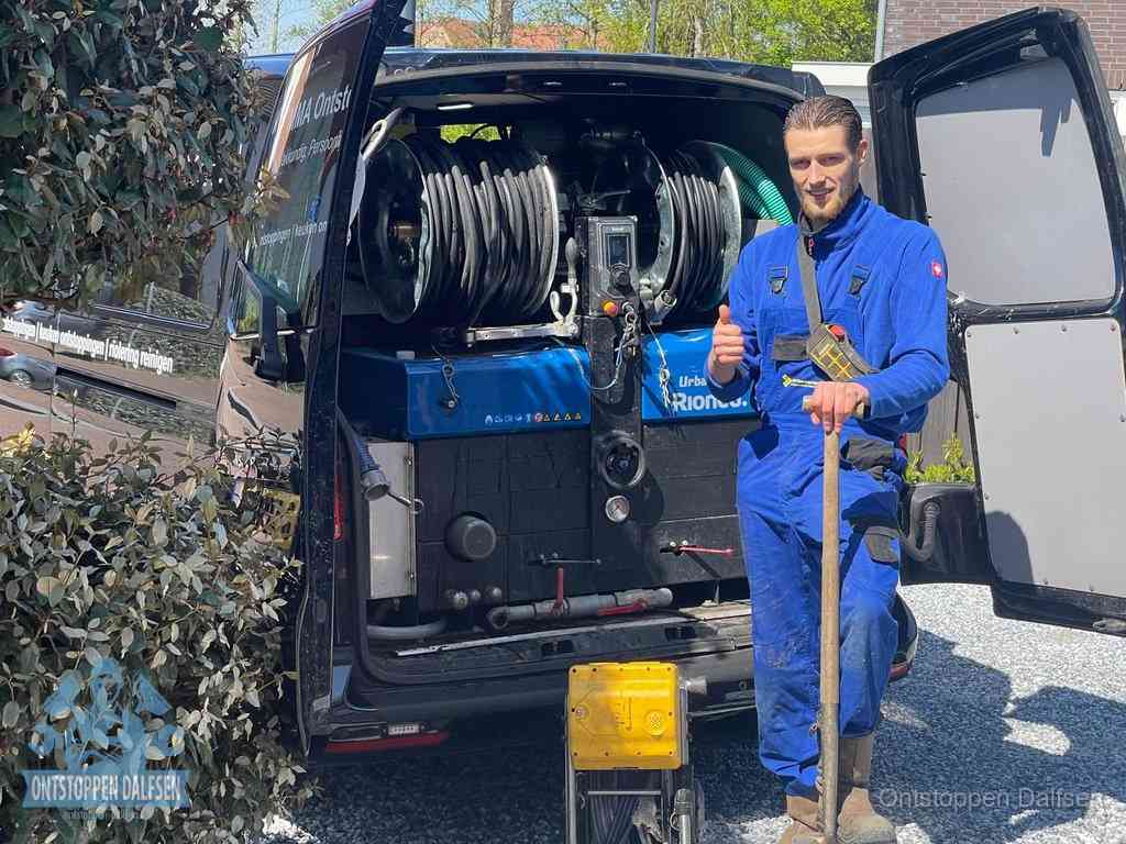 Professioneel rioolontstoppingsbedrijf in Dalfsen Lachende monteur bij de volle rioolreinigingsbus, een professioneel rioolontstoppingsbedrijf in Dalfsen