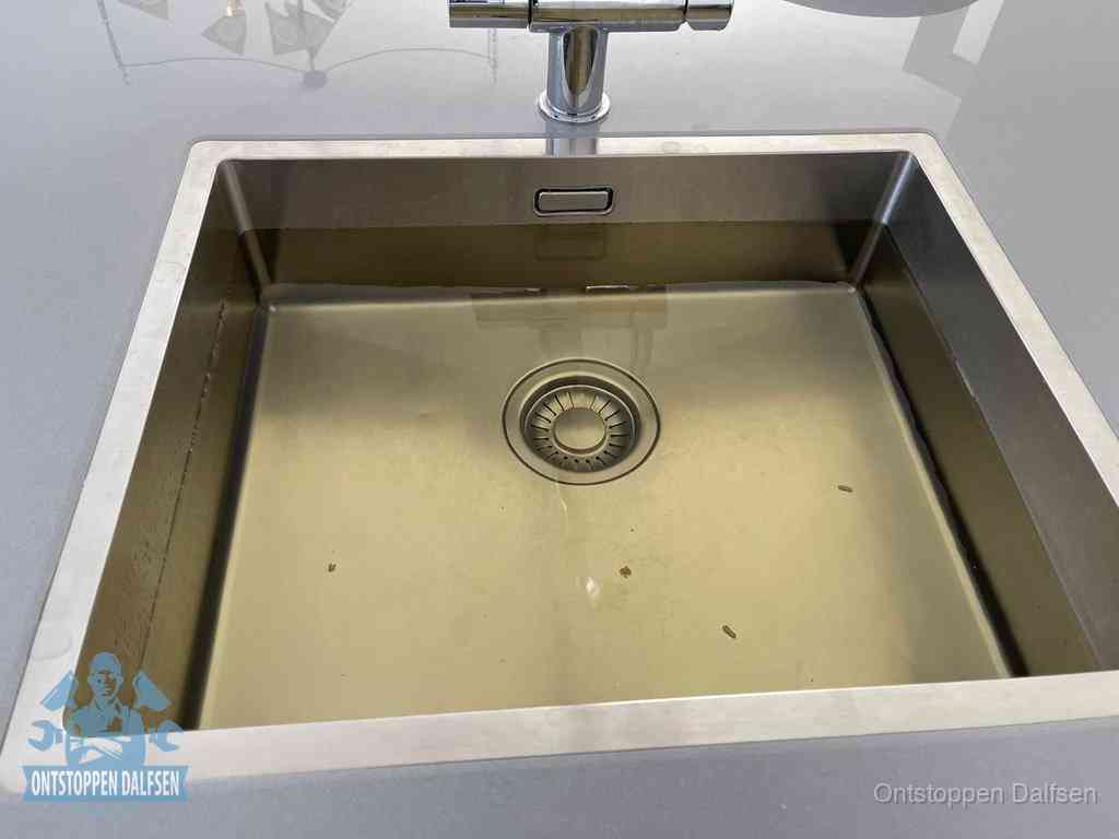 Stilstaand water in een rvs spoelbak dat niet wegloopt, een duidelijk signaal van een gootsteenverstopping in Dalfsen
