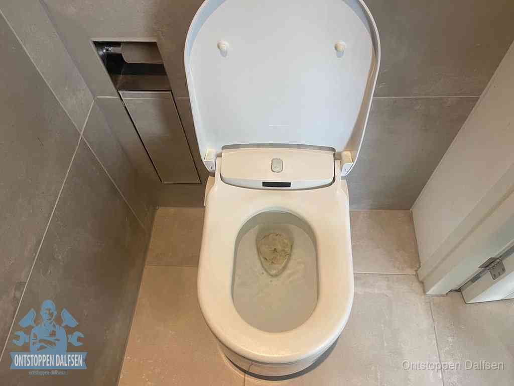 Een wit hangtoilet waarin een prop wc-papier op het water blijft drijven, een duidelijk signaal van een verstopte wc in Dalfsen