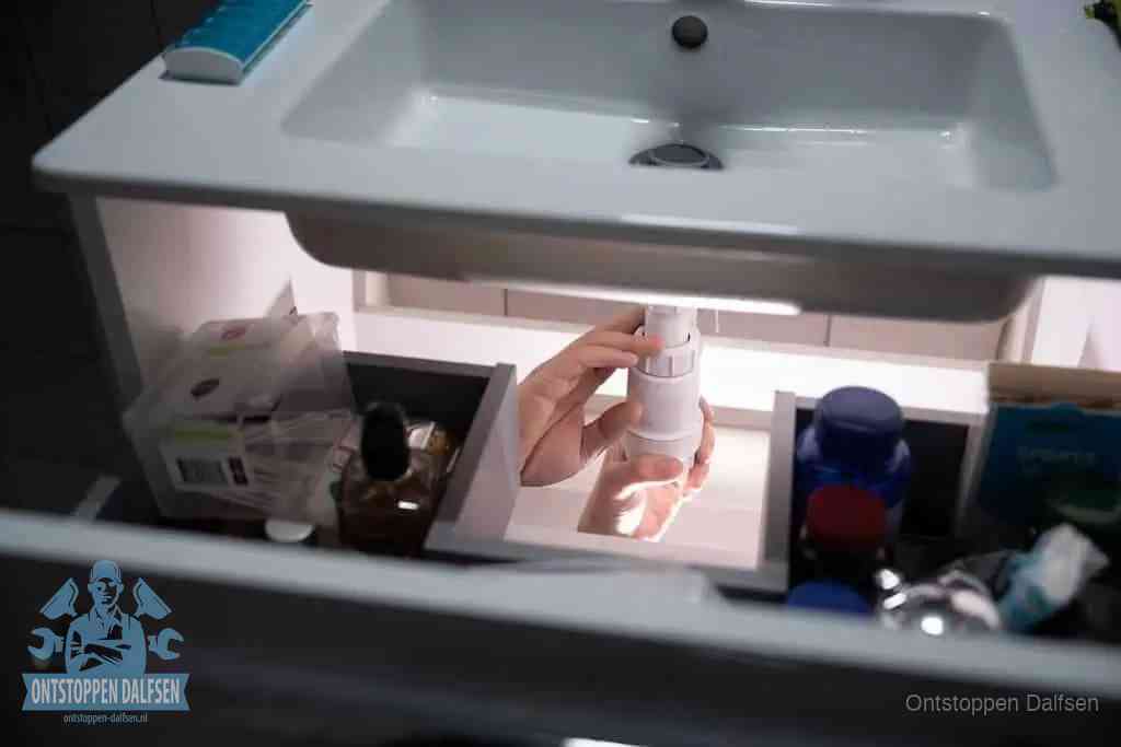 Een pompfles met zeep boven een wastafel in de toiletruimte, de warm water en afwasmiddel-methode om de wc te ontstoppen in Dalfsen