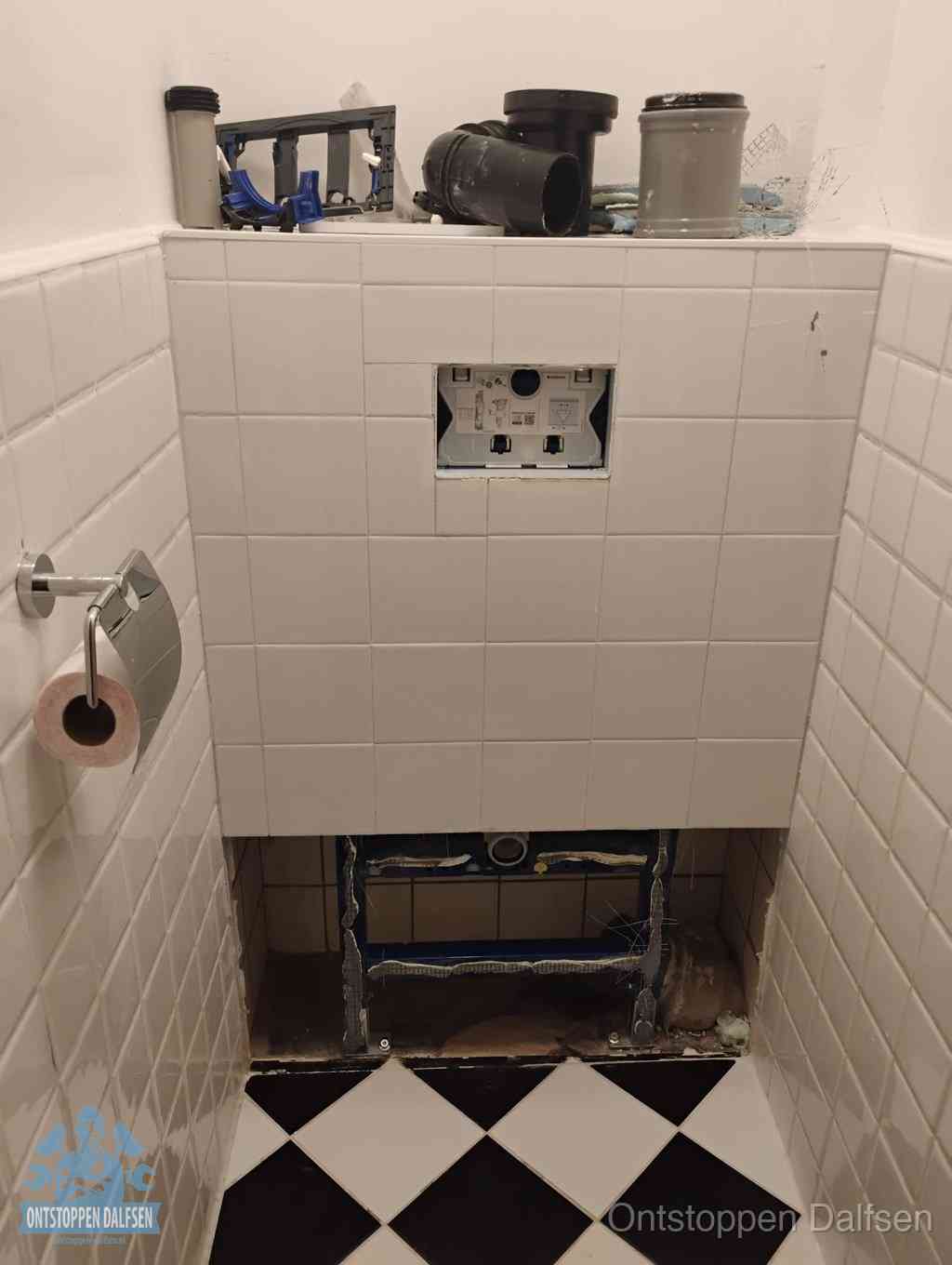 Een toiletruimte waar het hangtoilet en de inbouwreservoir-onderdelen zijn vrijgelegd voor onderhoud, periodiek nazicht voorkomt een wc-verstopping in Dalfsen